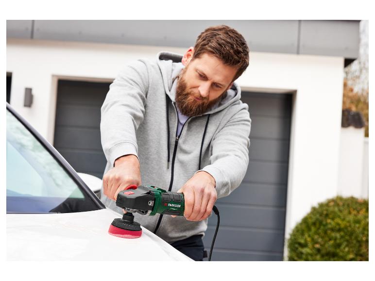 Een man poetst een witte auto met een Parkside polijstmachine.