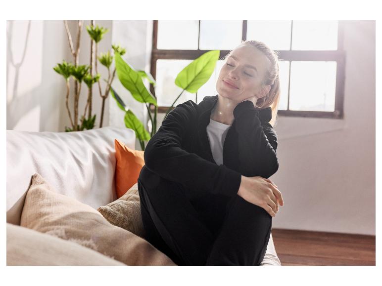 Ontspannen vrouw op een bank, gekleed in een comfortabele zwarte outfit.