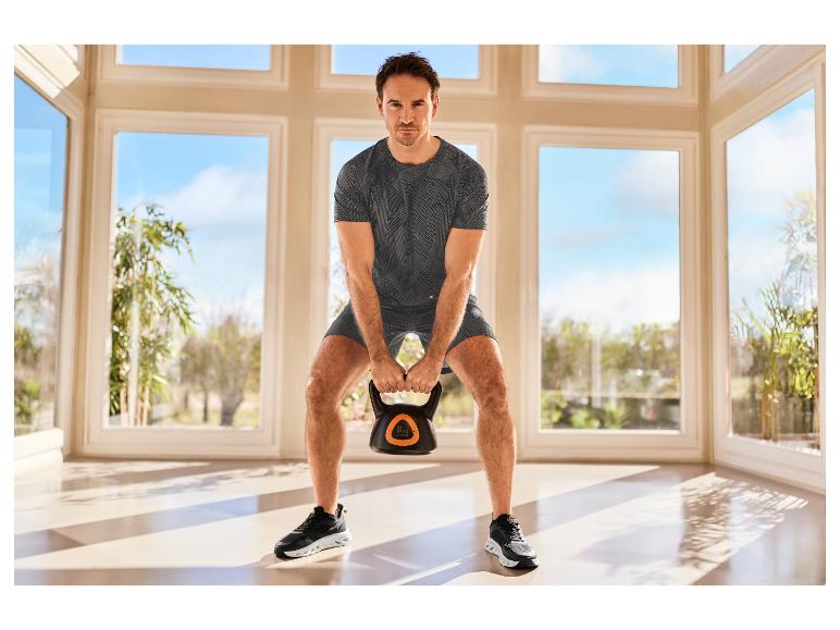 Man in CRIVIT-sportkleding traint met een kettlebell.