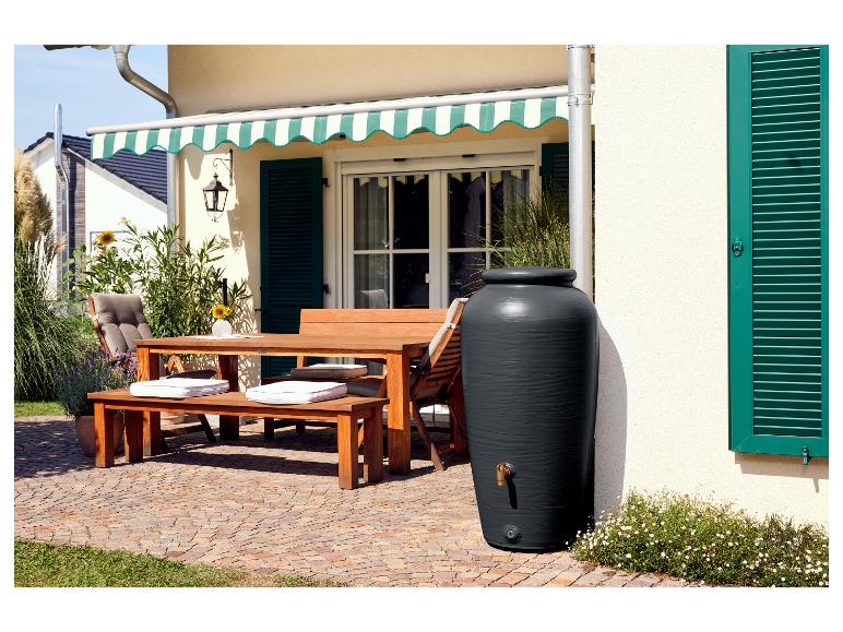 Terras met houten tafel, banken en een zwarte regenton.