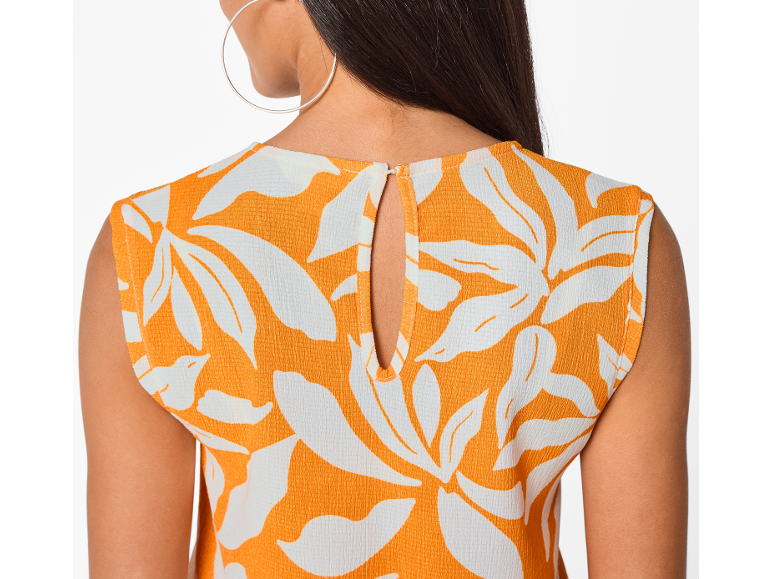 Rug van een vrouw in een oranje top met witte bloemenprint en een uitsnede.