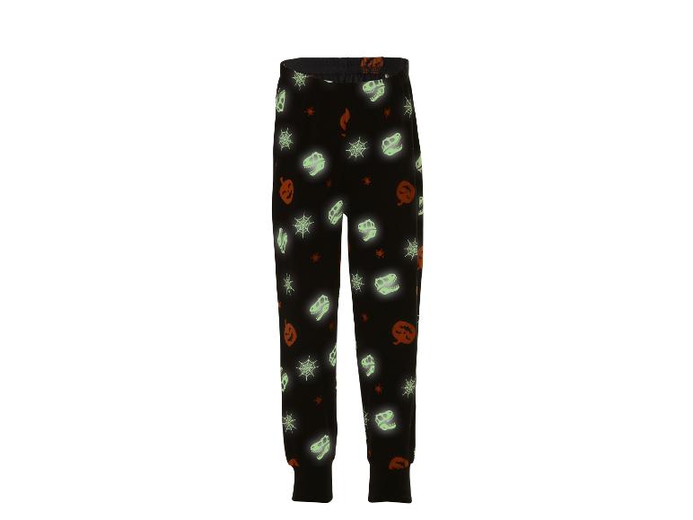 Zwarte pyjamabroek met Halloween-thema: pompoenen, spinnenwebben en dinosauruskeletten.