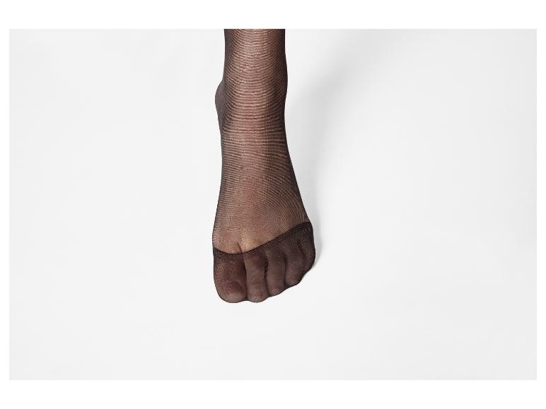 Vrouwenvoet met zwarte panty op een witte achtergrond.