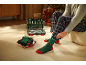 Een man in een geruite pyjamabroek trekt groene kerstsokken aan naast een gereedschapskist.