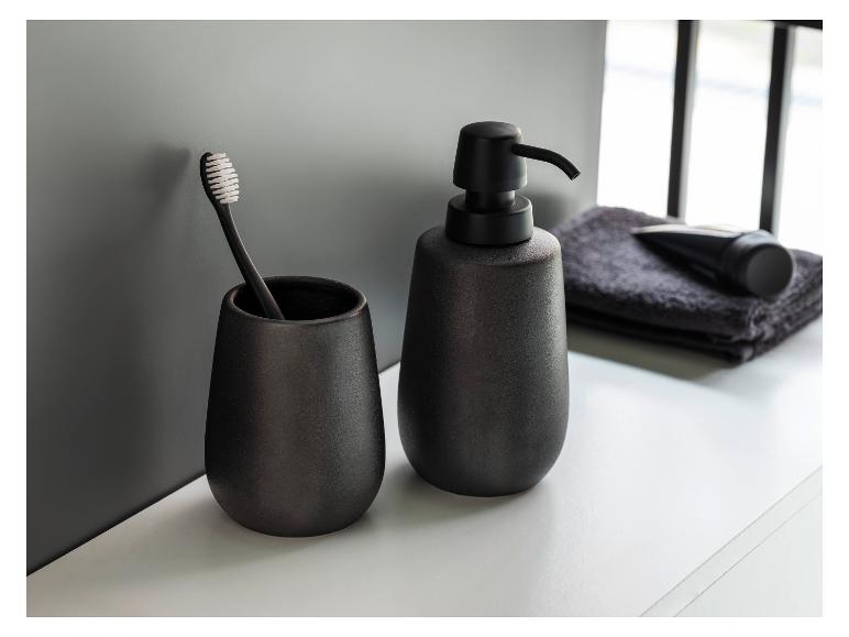 Zwarte keramische zeepdispenser en beker voor tandenborstel.