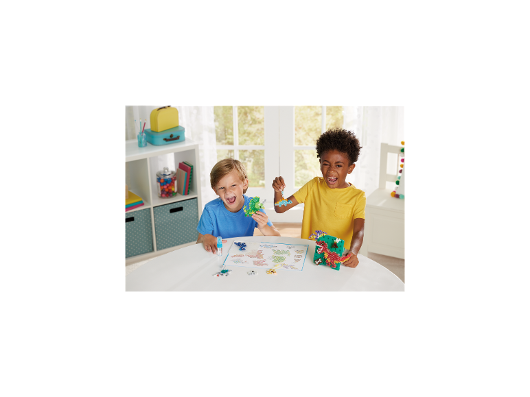 Twee jongens lachen terwijl ze dinosaurusvormige knutselkralen vasthouden.