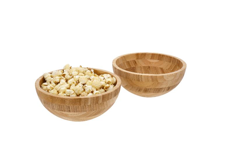 Twee houten kommen, één gevuld met popcorn, de andere leeg.