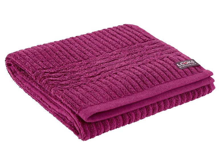 Gevouwen magenta handdoek met een gestructureerd patroon en een zwart label.