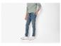 Man met lichtgroene trui, blauwe jeans en witte sneakers