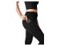 Vrouw in zwarte crop top en legging, stopt telefoon in zijzak.