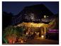 Mensen genieten van diner op terras met kleurrijke LED-verlichting en barbecue.
