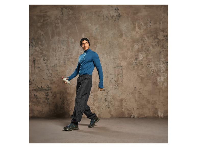 Man met blauwe trui, zwarte broek en wandelschoenen