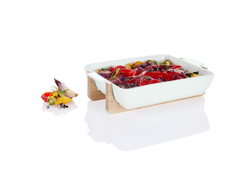 Witte ovenschaal met geroosterde groenten, voornamelijk rode paprika's.