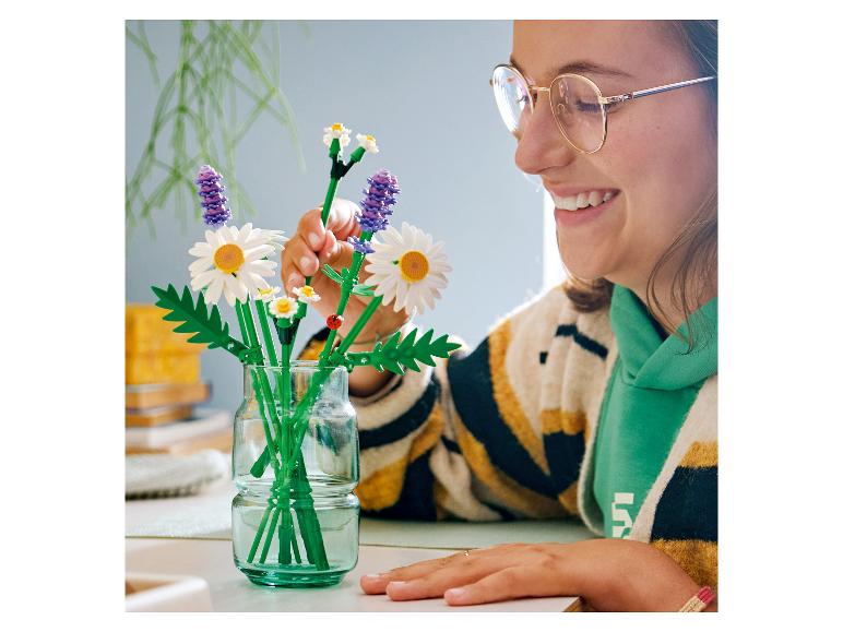 Vrouw schikt een boeket van LEGO BOTANICALS Gänseblümchen in een vaas.