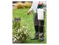 Persoon besproeit planten in een tuin met een schoudergedragen drukspuit.