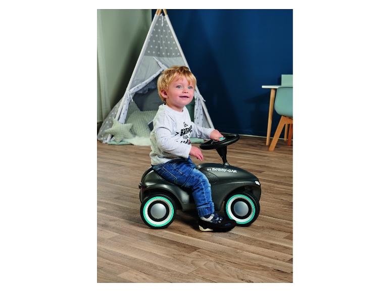 Peuter rijdt op een loopauto in een kamer met een speeltent.