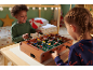 Twee kinderen spelen met een houten tafelvoetbalspel in een gezellige kamer