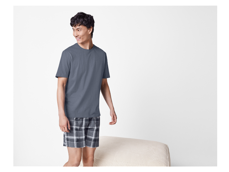 Man in grijs t-shirt en geruite short.