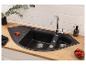 Zwarte dubbele spoelbak met kraan, geïntegreerd in een houten aanrechtblad.