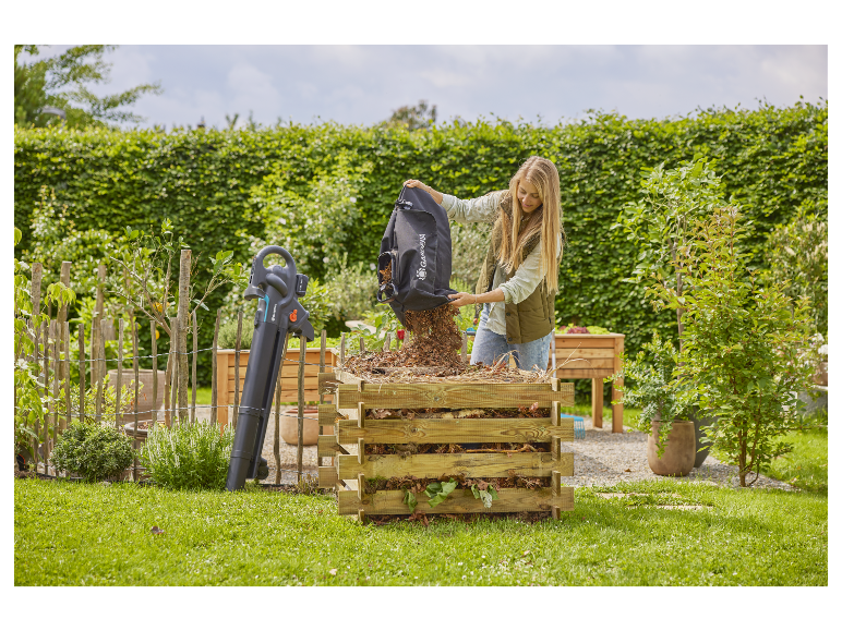 Vrouw vult een composthoop met bladeren via een Gardena bladblazer-zuiger.