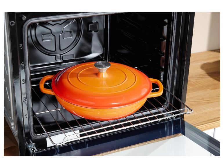 Een oven met een oranje Silvercrest gietijzeren pan erin.