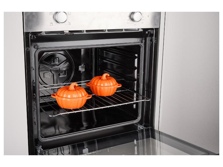 Oven met twee oranje pompoenvormige schaaltjes op een rooster.