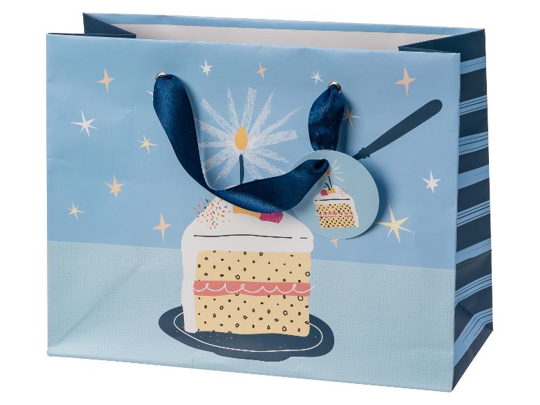 Blauwe cadeauzak met een verjaardagstaart, kaarsen en sterren, met een cupcake-cadeaulabel.