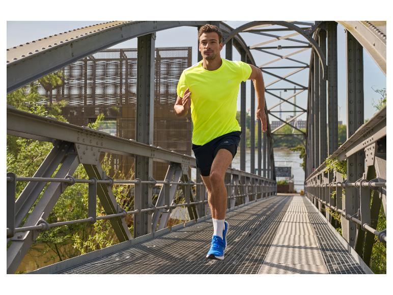 Man rent over een brug in een geel shirt en blauwe hardloopschoenen.