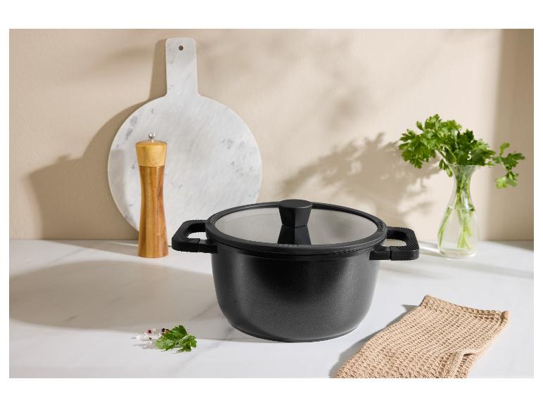 Zwarte pan met deksel, pepermolen, snijplank en peterselie in de keuken.