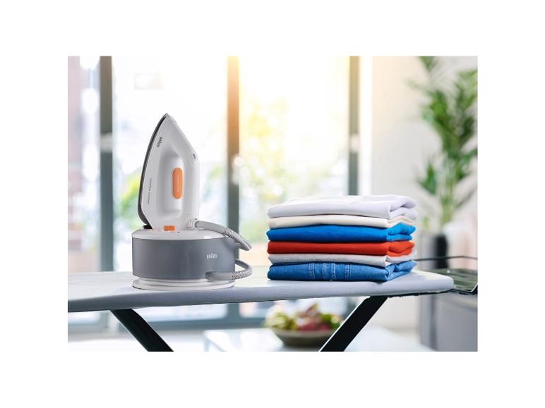 Braun strijkijzer met een stapel opgevouwen kleding op een strijkplank.