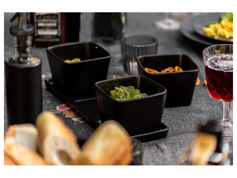 Zwarte kommen met guacamole, pretzels en stokbrood op tafel.