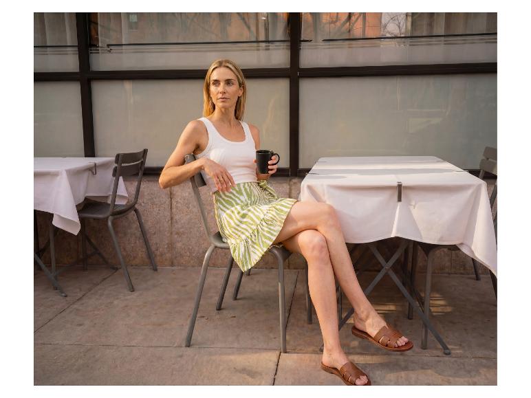 Vrouw in ESMARA® wikkelbroekrok zit op een terras met een mok koffie.