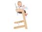 Baby zit in een houten en witte kinderstoel met een dienblad.