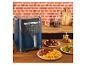 Een blauwe airfryer op een aanrecht met eten en accessoires.