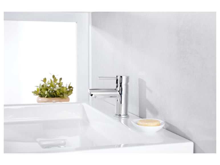 Een moderne chromen kraan op een wit wastafel.