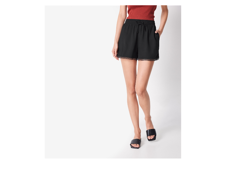 Zwarte shorts met gezoomde rand en platte sandalen: zomermode.