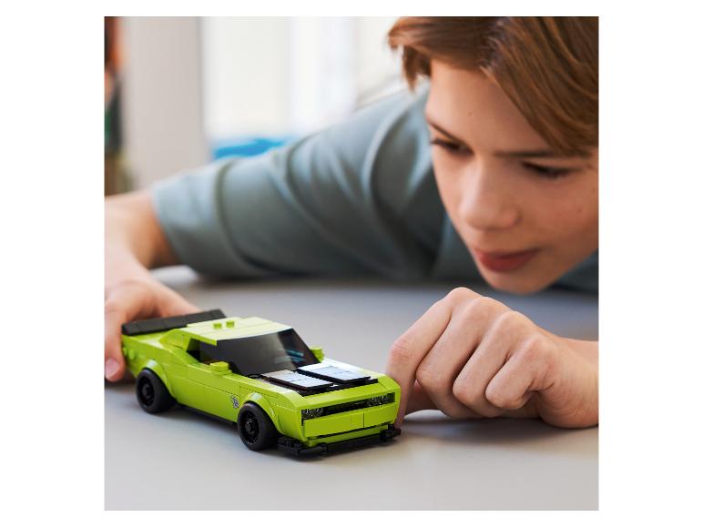 Een kind speelt met een groene sportwagen van bouwstenen.