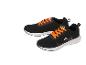 Een paar zwarte sportschoenen met oranje veters en decoratieve details.