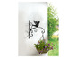 Een zwarte metalen plantenhanger met vogelmotief, met daarin een hangende plantenmand met bloemen.