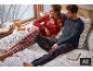 Heren- en damesflanellen pyjama's met ruitpatroon in een gezellige thuisomgeving.