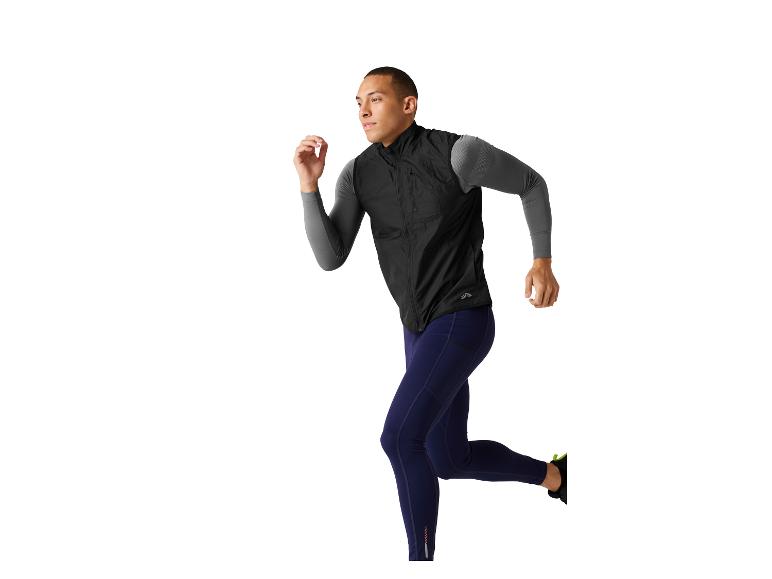 Man in donker gekleurde leggings en vest aan het rennen.
