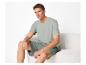 Man in lichtgroen V-hals T-shirt en korte broek zit op een bank.