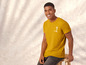 Man in een geel T-shirt met een palmboomprint.