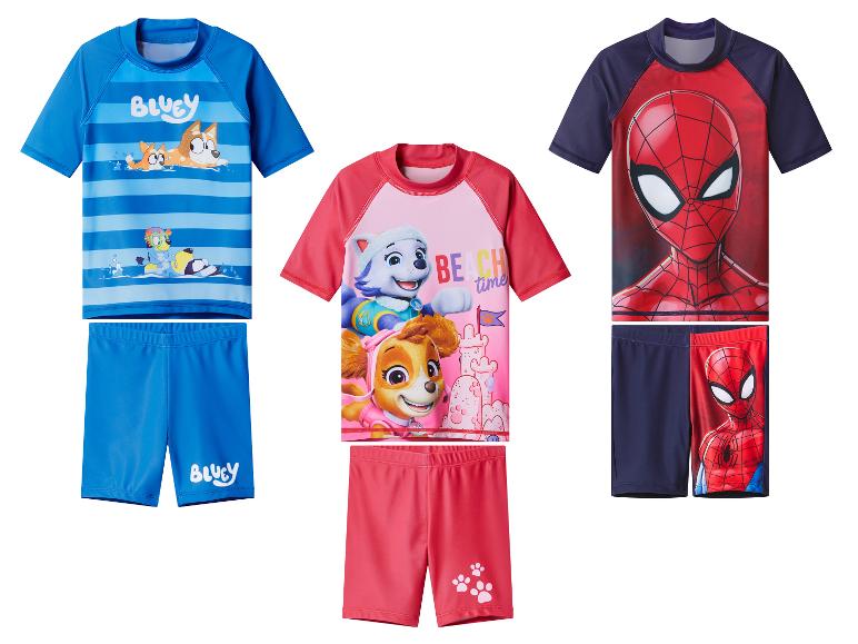 Drie sets kinderzwemkleding: blauw met tekenfilmhonden, roze met tekenfilmhondjes en rood/marineblauw met een superheld.