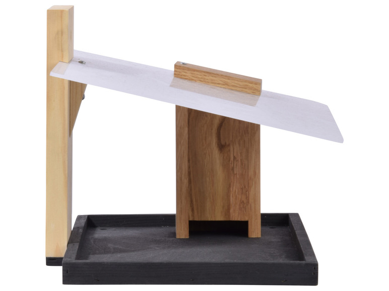 Een houten vogelvoederhuisje met een dakje en een zwarte ondergrond.