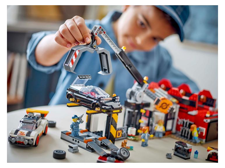 Een jongen speelt met een LEGO City autogarageset, inclusief auto's en minifiguren.