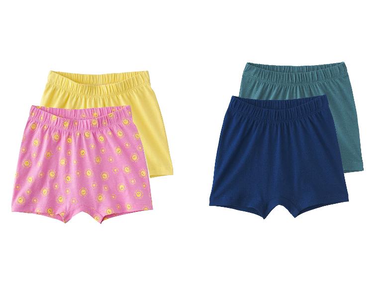 Twee paar kinderboxershorts: één roze met zonnetjes en één gele, en één marineblauwe met een teal.