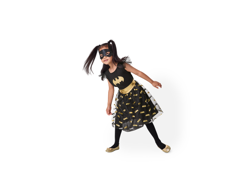 Meisje in zwarte Batman-jurk met gouden schoenen.