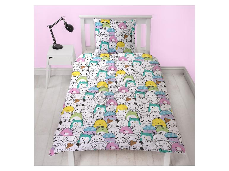 Kinderdekbedovertrek met kleurrijke, cartoonachtige dieren op een bed met wit frame.