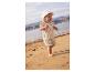 Baby in zonnehoed en bloemenoutfit op het strand.